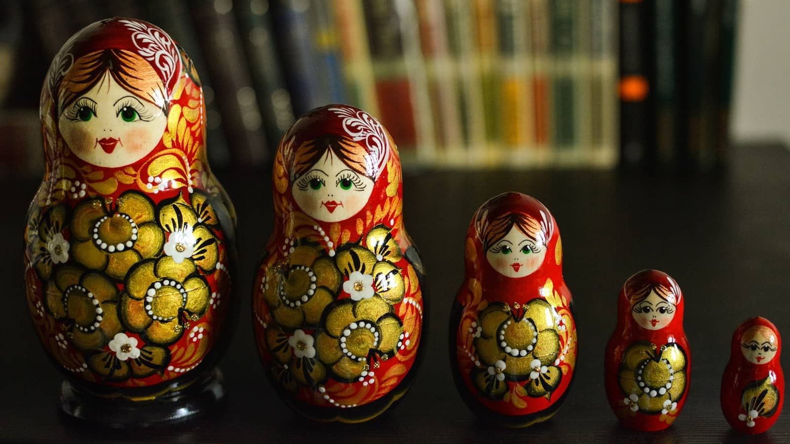 Colorful nested Russian dolls arranged in a row, representing layered state management concepts and the hierarchical nature of React Context and Redux stores